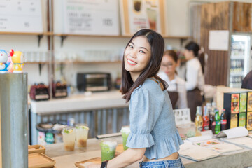 Asian smiling women with ice matcha green tea in art cafe