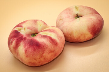 two chinese flat peaches isolated on orange 