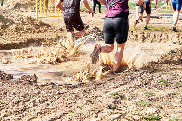 Group of participants in an obstacle course race running across a pool of water. Spartan race....