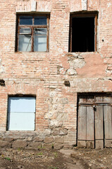 Brick wall with windows and closed wooden door of an old abandoned building