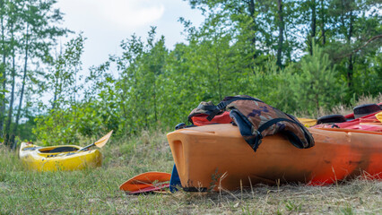 Camping with kayaks on the beach of river on a sunny day. Modern kayaks with paddles on beach near river.