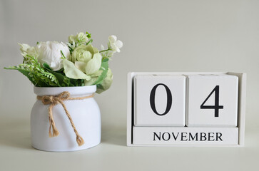 November 4, Cover natural background, white wooden Calendar cube with a pot flower on white background.