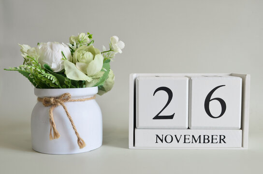 November 26, Cover natural background, white wooden Calendar cube with a pot flower on white background.