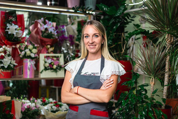 Portrait of young smiling owner standing at her flower shop. Entrepreneur leaning with her arms crossed and smiling confidently at the camera. Startup of small business owner and service mind concept.