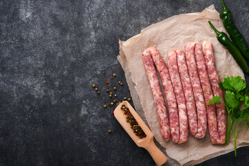 Raw sausages. Bratwurst or sausages with ingredients on cutting board with spices on a stone background with copy space. Food cooking background. Top view.