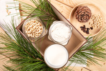 Wooden box with cedar milk glass, jars of flour and nuts, cone, branches on wooden close up.