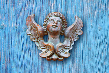 Wooden sculpture of an italian angel against a woodem background - more than 100 years old