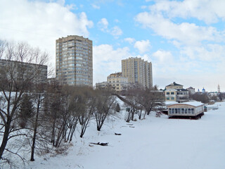 Tall buildings that stand on the banks of a frozen river.