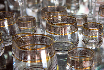 Lots of empty, clean glasses with a gold rim. Retro tableware. Background, texture