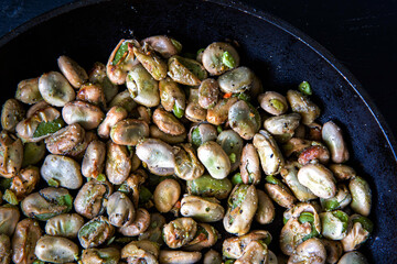 Broad beans stewed with onion and spices in a pan