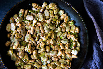 Broad beans stewed with onion and spices in a pan