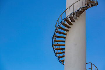 Curved stairway of base oil storage tank in the petroleum factory with blue sky. Industrial...