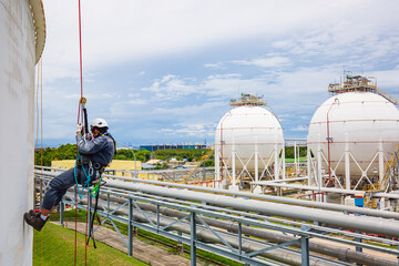 Focus top view male worker down height tank roof rope access safety inspection of thickness storage...