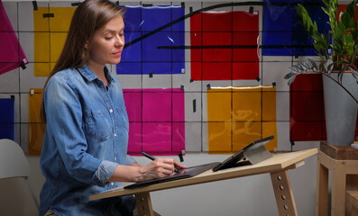 Serious woman designer working at home, wall with red, blue, yellow color palette