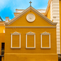 side of the cathedral, yellow catholic church with details on the windows without glass