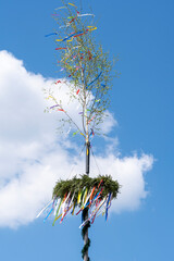 Maypole with wreath with ribbons in Germany against a sky with clouds - obrazy, fototapety, plakaty