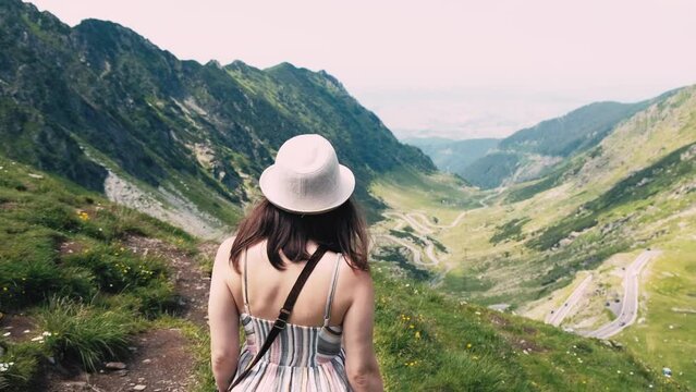 Footage of young woman in dress walking near Transfagarasan Beautiful Road during summer day.