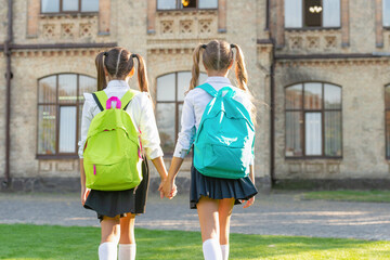 back view of two children with school backpack walking together outdoor. copy space