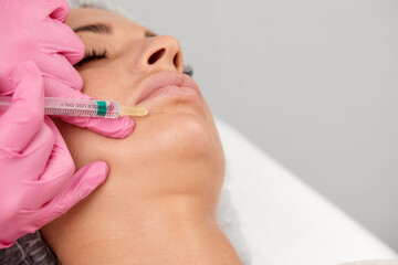Obraz na płótnie Canvas Woman getting cosmetic injection of botox in cheek, closeup. Woman in beauty salon. plastic surgery clinic