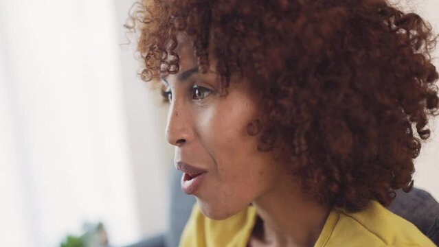 Woman eating popcorn while watching tv at home. Happy female laughing while eating snacks and enjoying a funny comedy movie on television. Enjoying a weekend of entertainment with sitcom shows