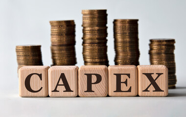 CAPEX - acronym on wooden cubes on the background of stacks of coins - obrazy, fototapety, plakaty