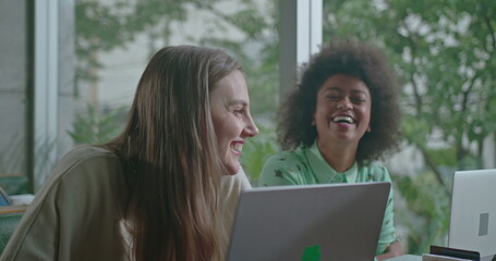 Group of three women talking at coffee shop. Friend sharing story with colleagues laughing and smiling. Diverse female friends having fun together