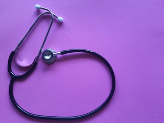 Fototapeta premium Stethoscope, isolated on a pink background, top view. Awareness of female diseases, breast cancer.