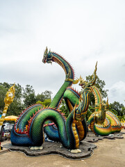 Fototapeta premium Ubon Ratchathani, Thailand - July 10, 2022: Tourists visit the Naga statue in Nong Bua Temple, Ubon Ratchathani Province, Thailand.