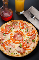 pizza with a glass of orange juice on a dark background