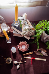 Altar with several books, plants, candles, semiprecious stones and matches tied with red thread..