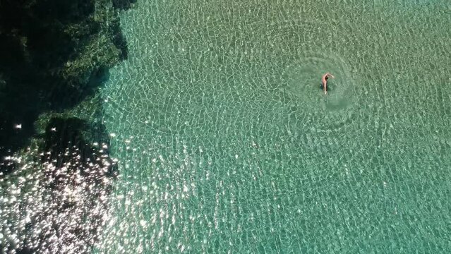 Aerial view over Chrisi Milia beach with tourists enjoying swimming by the rocky surrounded area in Alonissos island, Greece