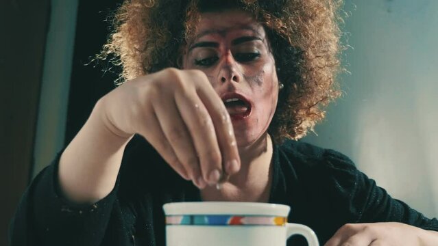 lonely and depressed alienated young woman dips cookies in the cup of milk