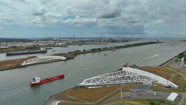 Ship passing the Maaslantkering in the Nieuwe Waterweg from the port of Rotterdam towards the North Sea. Aerial view drone footage from above.