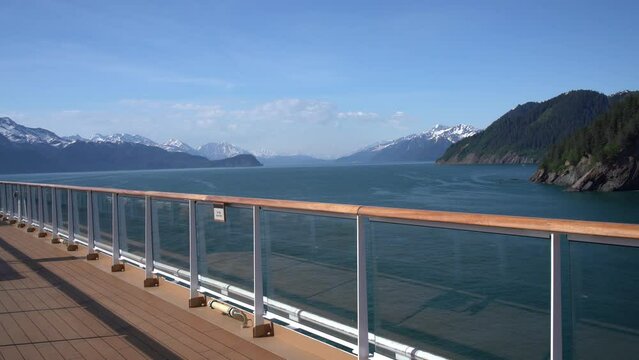 Static video shot of a cruise ship sailing away from Seward in Alaska and then senior adult man stands on deck of boat and watches the scenery on sunny warm day