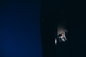 Fototapeta premium Senior manager is alone in the office at night, drinking coffee and looking out the window.