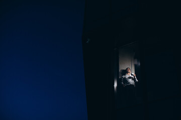 Fototapeta premium Senior manager is alone in the office at night, drinking coffee and looking out the window.