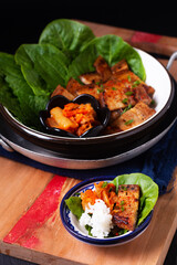 Asian food concept homemade Korean Grilled pork belly BBQ Samgyeopsal-gui with kimchi and shiso and salad on black background with copy space