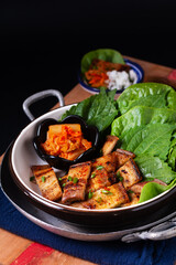 Asian food concept homemade Korean Grilled pork belly BBQ Samgyeopsal-gui with kimchi and shiso and salad on black background with copy space