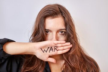 A beautiful girl in a black shirt covers her mouth with her hand with the inscription 