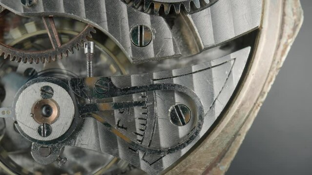 Internal vintage clockwork mechanism macro. Rotating silver gears, metal gearing, tootheds wheels. Disassembled watch with screws, cogwheels and winding spring. Open working clockwork. Rack focus.