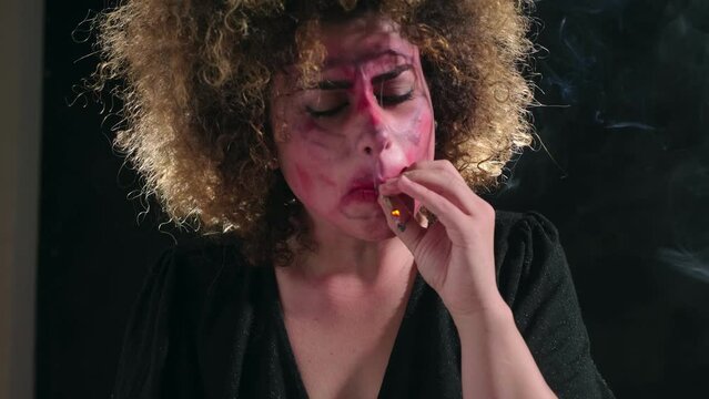 psychotic young woman with a dirty face smoking a joint in the throes of retching