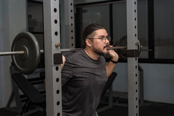 A man in his late 30s makes a comeback at the gym. Doing back squats with a relatively light...