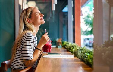Portrait of a healthy young happy woman drinking a juice in cafe
