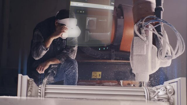 A worker in a vr headset watches the milling process, using augmented reality technology to remotely control and visualize the 3D model and the process of completing the task with a robotic arm.