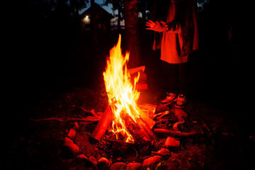 Girl tourist, warming herself by the fire at night in a tourist camp. 