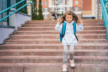 Back to elementary, primary school. Little sad girl with big backpack goes in hurry, late to first grade alone in autumn morning. Education, future of children. Happy,unhappy pupil kid on stair steps