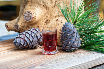 a glass swiss stone pine schnapps, cones and twigs from the swiss stone pine or arolla on a wood board