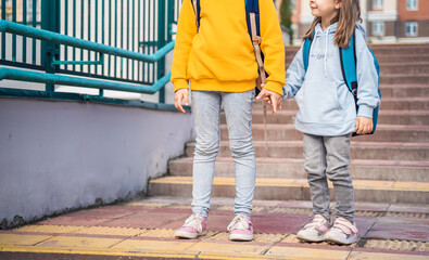 Fototapeta premium Back to elementary,primary school.Little girls,sisters with big backpacks go in hurry,late to first grade alone in autumn morning.Education,future of children.Happy,unhappy pupils kids on stair steps