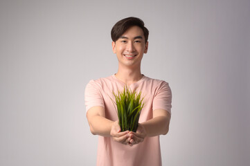 Young smiling man holding tree over white background studio, save earth concept