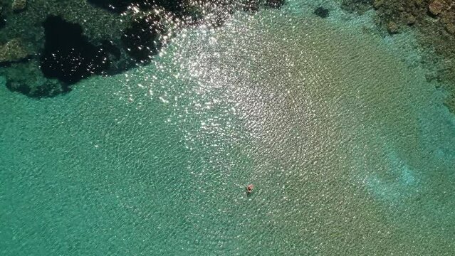 Aerial view over Chrisi Milia beach with tourists enjoying swimming by the rocky surrounded area in Alonissos island, Greece